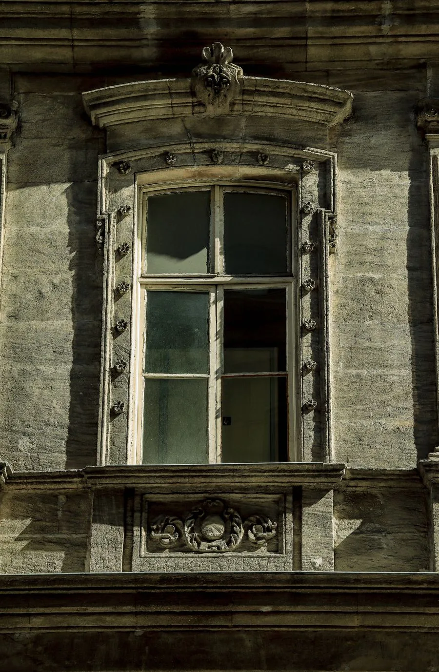 Kamenný venkovní parapet z béžového travertinu u okna s bílým rámem